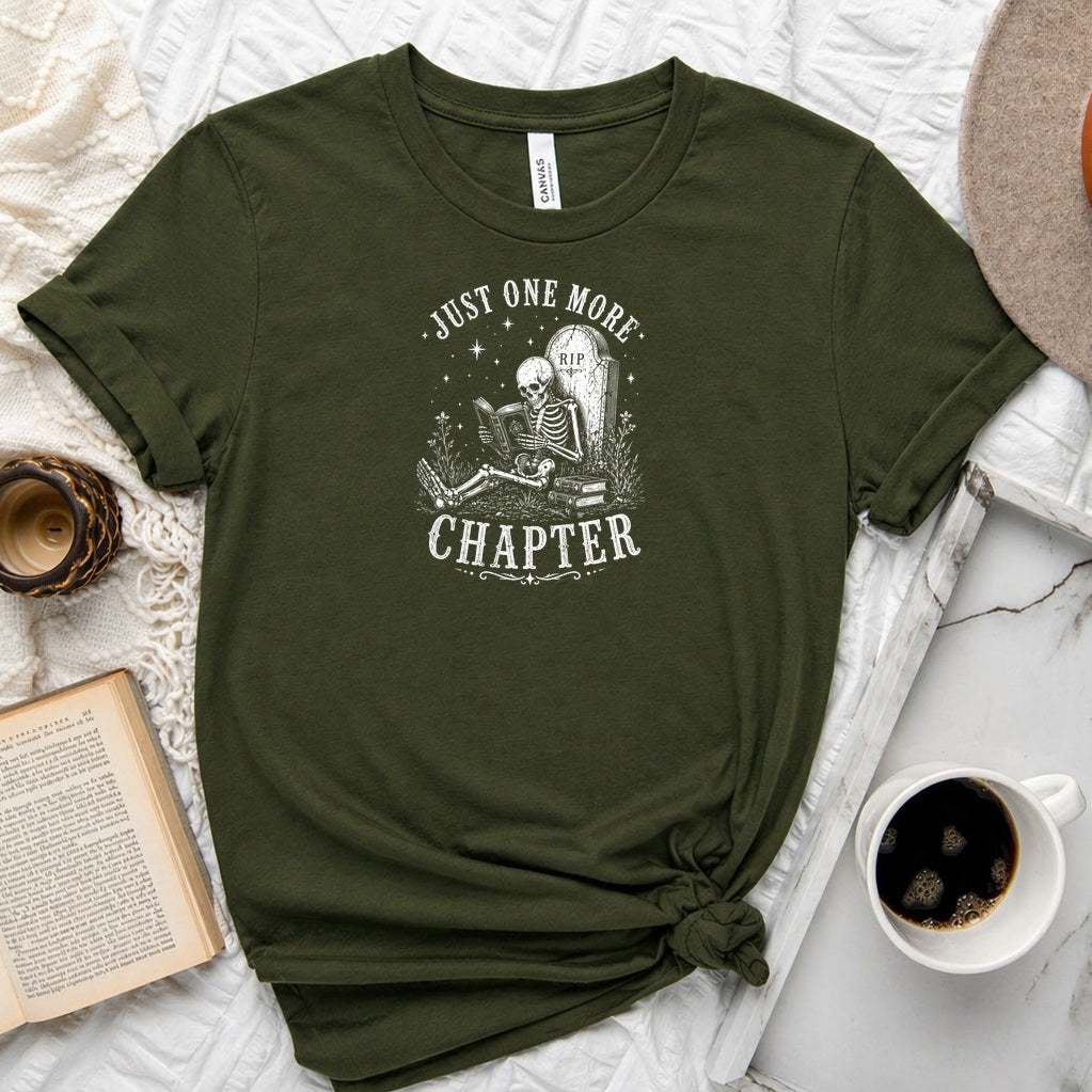 Just One More Chapter unisex tee with vintage skeleton reading in armchair surrounded by stacked books and wildflowers graphic
