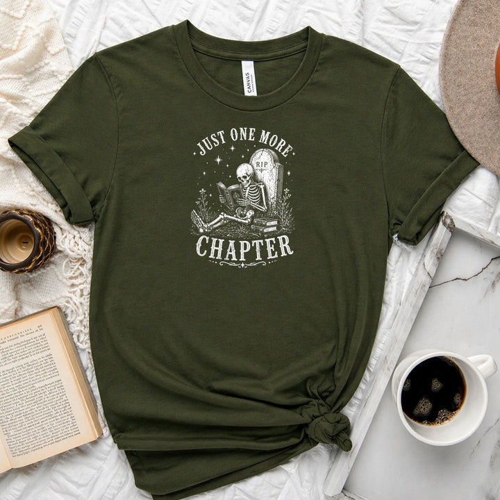 Just One More Chapter unisex tee with vintage skeleton reading in armchair surrounded by stacked books and wildflowers graphic