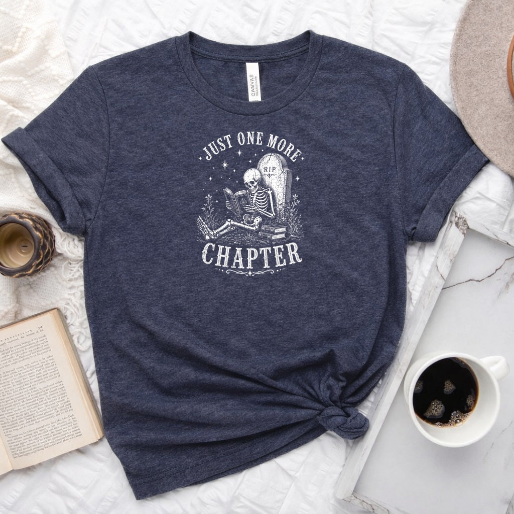 Just One More Chapter unisex tee with vintage skeleton reading in armchair surrounded by stacked books and wildflowers graphic
